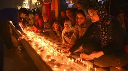 Umat Sikh menyalakan lampu tanah di Kuil Emas yang diterangi pada peringatan kelahiran Guru Nanak di Amritsar, India, 19 November 2021. Guru Nanak adalah Guru Sikh pertama dan pendiri Sikhisme. (AP Photo/Prabhjot Gill)