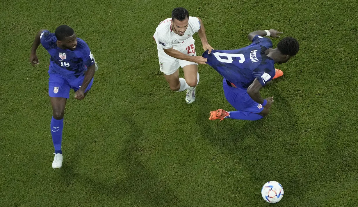 Bek Iran Abolfazi Jalali  memegang jersey gelandang Amerika Serikat Yunus Musah pada laga pamungkas Grup B Piala Dunia 2022 di Stadion Al Thumama, Rabu (30/11/2022) dini hari WIB. Iran mencoba membalas, namun hingga laga usai tak ada lagi gol tercipta. (AP Photo/Hassan Ammar)
