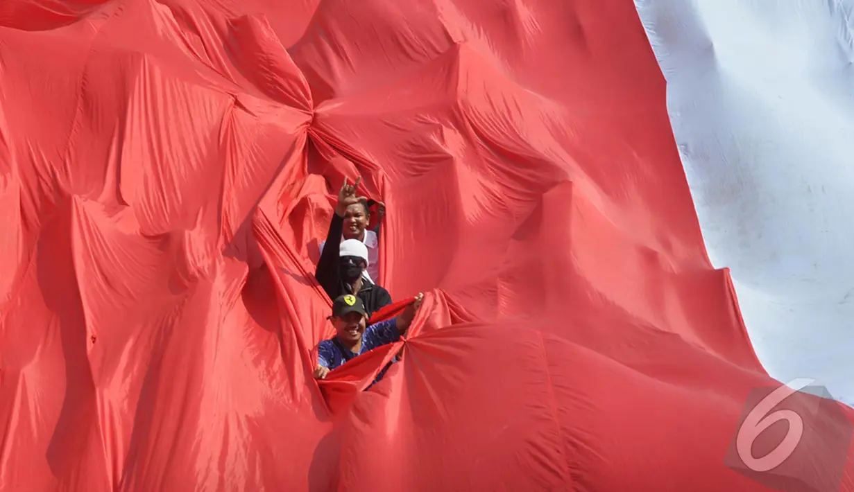 Sejumlah relawan membentang bendera Merah Putih raksasa saat mengikuti kirab budaya, Jakarta, Senin (20/10/2014) (Liputan6.com/Miftahul Hayat) 