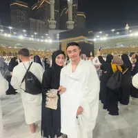 Momen berikutnya memperlihatkan keduanya berpose mesra di depan Ka'bah. Putri Zulhas tampil anggun dalam gamis putih dengan aksen renda emas yang memberikan kesan mewah namun tetap sopan.  [@zumizolazulkiflinurdin].
