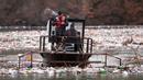 Pekerja perusahaan utilitas mendorong limbah ke tepi Sungai Lim dekat Priboj, Serbia, 30 Januari 2023. Botol plastik, papan kayu, tong berkarat, dan sampah lainnya dari tempat pembuangan sampah tepi sungai yang tidak diatur dengan baik terakumulasi selama air pasang. (AP Photo/Armin Durgut)