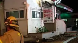 Pemandangan aneh sebuah mobil yang tertancap di bangunan lantai dua klinik dokter gigi di Santa Ana, California, Minggu (14/1). Pihak kepolisian setempat meyakini pengemudi mobil itu terpengaruh atau mabuk narkotika. (Orange County Fire Authority via AP)