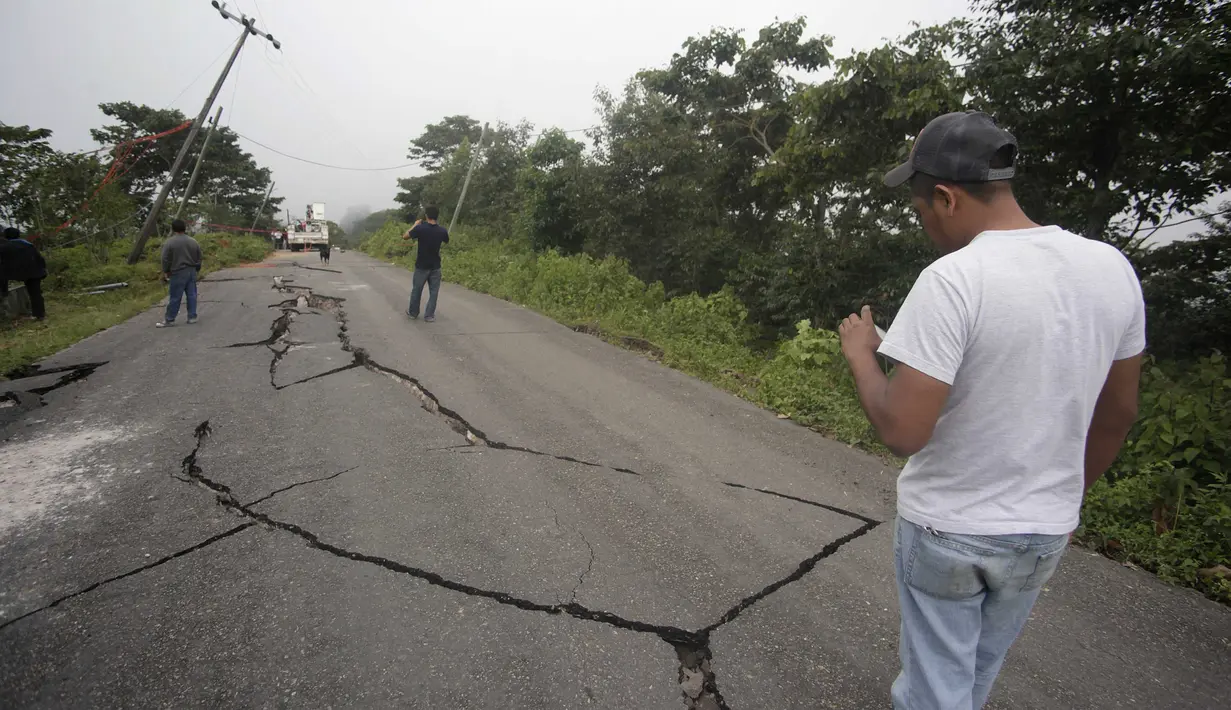 Seorang warga mengambil gambar sebuah jalan yang retak akibat gempa di San Marcos, Guatemala, Senin (7/7/14). (REUTERS/Mario Castillo)