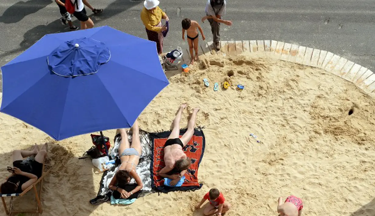 Para wisatawan berjemur di pantai buatan Paris Plages , Perancis, Rabu (22/7/2015).  Tahun ini adalah edisi ke-14 dari Paris Plages, acara budaya dan wisata utama di Paris selama musim panas. (AFP Photo/Miguel Medina)