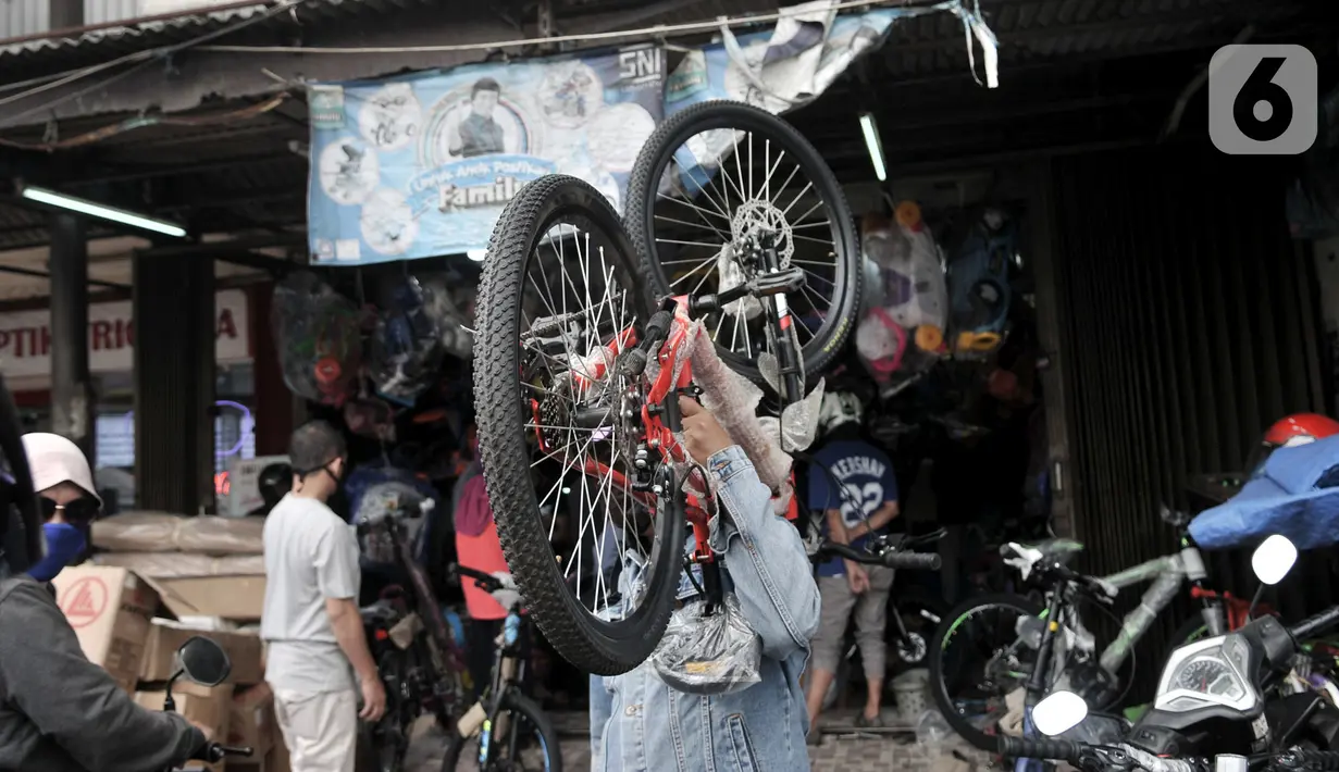 Warga memikul sepeda yang baru dibeli di sebuah toko di Kramat Jati, Jakarta, Minggu (21/6/2020). Dalam sebulan terakhir, penjualan sepeda di Ibu Kota meningkat hingga 50 persen seiring minat dan tren warga yang melonjak menggunakan transportasi gowes itu di masa pandemi. (merdeka.com/Iqbal Nugroho)