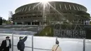 Orang-orang melihat Stadion Nasional Tokyo untuk Olimpiade dan Paralimpiade Tokyo 2020 setelah selesai direnovasi di Tokyo (30/11/2019). tadion berkapasitas 60 ribu itu akan menjadi venue upacara pembukaan serta berbagai nomor atletik dan cabang sepak bola. (Masanori Takei/Kyodo News via AP)