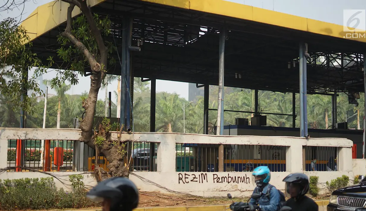 Pengendara melintas dekat Gerbang Pejompongan tol dalam kota yang rusak akibat dibakar massa di Jakarta, Rabu (25/9/2019). Kebakaran tersebut menyebabkan gerbang tol ditutup untuk sementara waktu sampai selesai proses perbaikan. (Liputan6.com/Immanuel Antonius)