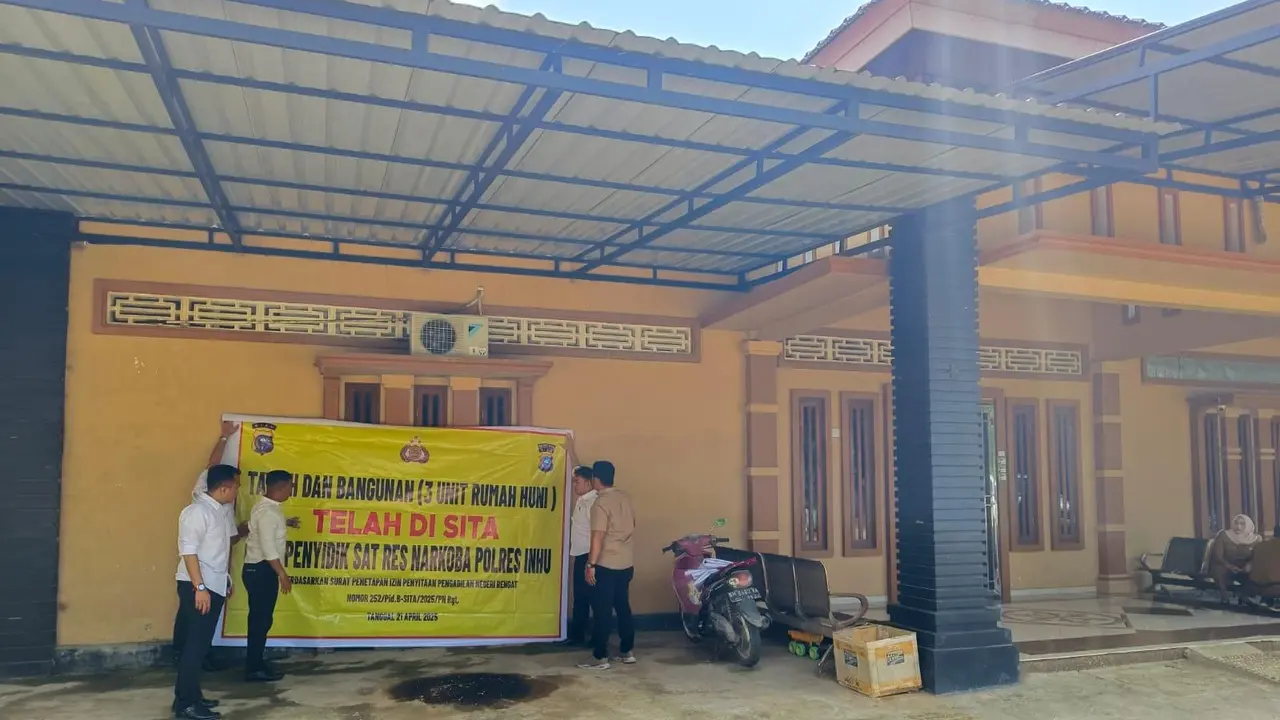 Personel Polres Indragiri Hulu memasang tanda sita di rumah ratu narkoba Inhu, Mak Gadi, dalam pengusutan tindak pidana pencucian uang.