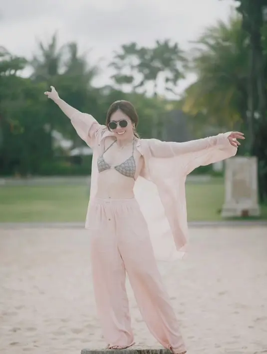 Wulan Guritno dengan swim bra yang ditumpuk mengenakan setelan oversized shirt transparan bernuansa oranye dan celana panjangnya yang serasi. [Foto: Instagram/wulanguritno]