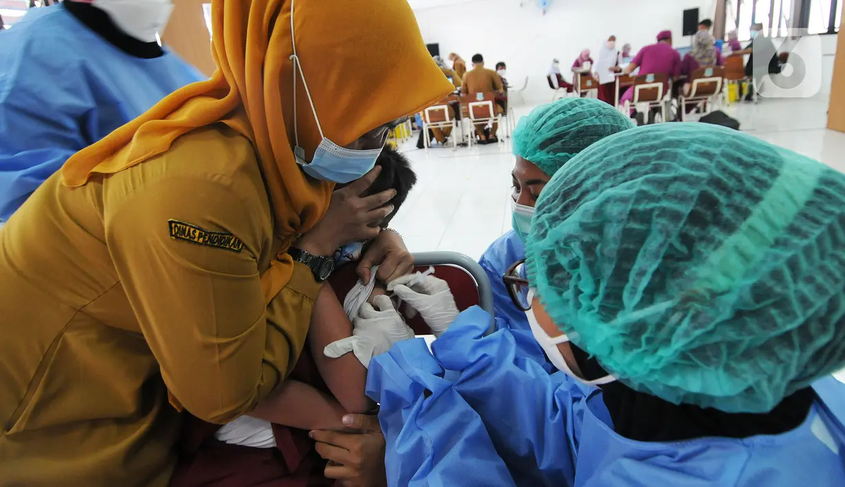 Petugas kesehatan menyuntikkan vaksin COVID-19 kepada siswa di SDN 02 Ciater, Tangerang Selatan, Selasa (14/12/2021). Mulai Hari ini, 11 provinsi di Indonesia secara serentak melaksanakan vaksinasi COVID-19 dengan sasaran anak berusia 6 hingga 11 tahun. (merdeka.com/Arie Basuki)