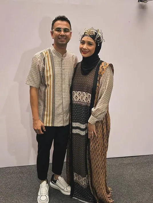 Nagita Slavina mengenakan gamis print dari Zaskia Sungkar warna earth tone dipadukan kerudung hitamnya. Raffi Ahmad kenakan kemeja kerah shanghai lengan pendek bermotif dan celana hitam. [@raffinagita1717]