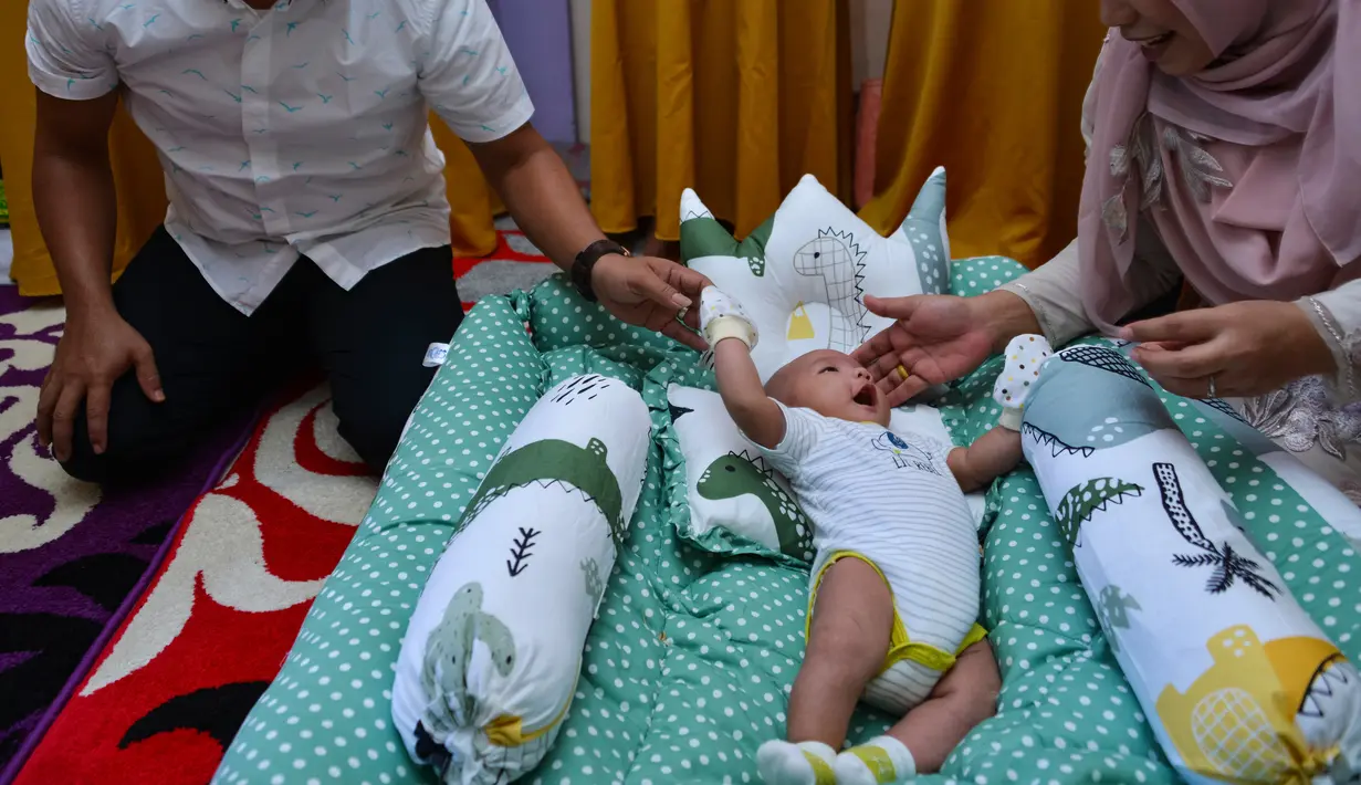 Tokoh adat dan agama mengendong bayi pada ritual 'peutron tanoh aneuk' (turun tanah anak) di Desa Alue Naga, Banda Aceh, Aceh, Senin (15/7/2019). Ritual turun tanah anak yang telah menjadi tradisi sakral bagi masyarakat Aceh yang dilaksanakan pada saat bayi berusia 44 hari. (CHAIDEER MAHYUDDIN/AFP)