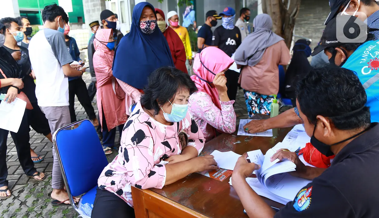 Warga antre menerima Bantuan Sosial Tunai (BST) di Kelurahan Pondok Benda, Kecamatan Pamulang, Tangerang Selatan, Minggu (10/01/2021). Sebanyak 92.737 kepala keluarga tercatat sebagai penerima BST di wilayah Tangerang Selatan senilai Rp300 ribu. (Liputan6.com/Fery Pradolo)