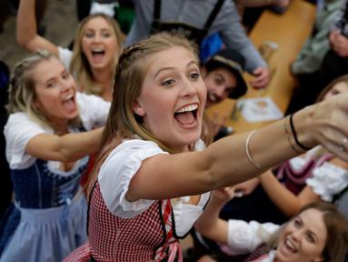 Seorang wanita mengambil gelas bir selama pembukaan festival bir Oktoberfest di 184, Munich, Jerman, (16/9). Festival ini diadakan dari tanggal 16 sampai 3 Oktober 2017. (AP Photo / Matthias Schrader)