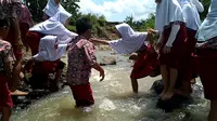 Siswa SDN 2 Patapan Kabupaten Cirebon bahu membahu menyebrangi sungai yang selalu dilewati mereka setiap hari. Foto (Liputan6.com / Panji Prayitno)