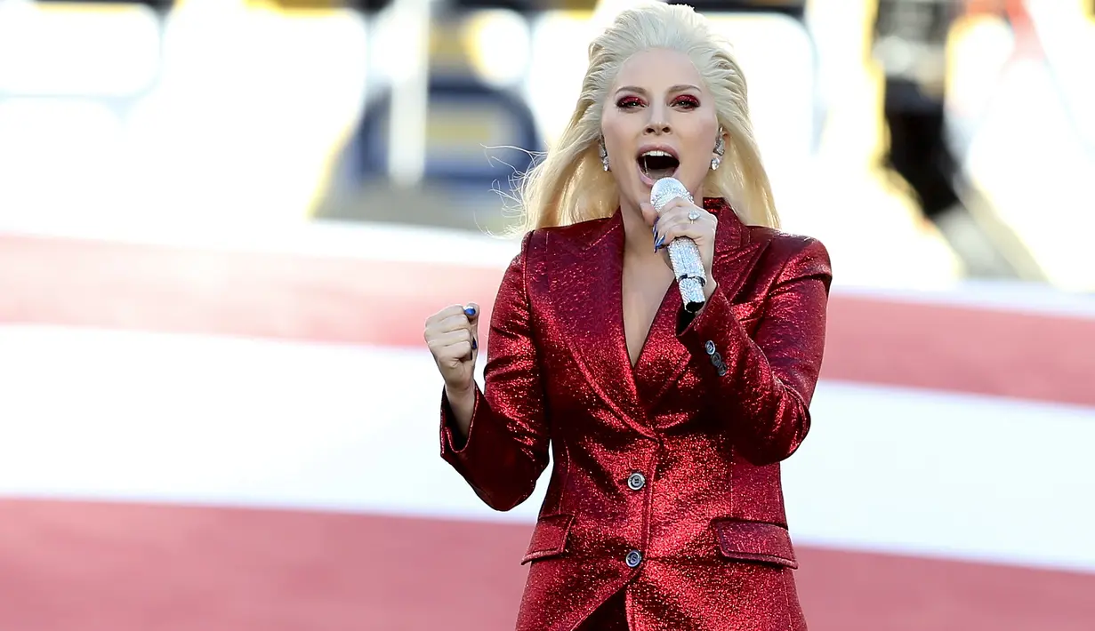 Penyanyi Lady Gaga menyanyikan lagu kebangsaan AS saat pembukaan Super Bowl 50 di Santa Clara, California, Minggu (7/2). Mengenakan busana dari Gucci, Mother Monster itu tampil serba merah seperti bendera negaranya. (Streeter Lecka/Getty Images/AFP)