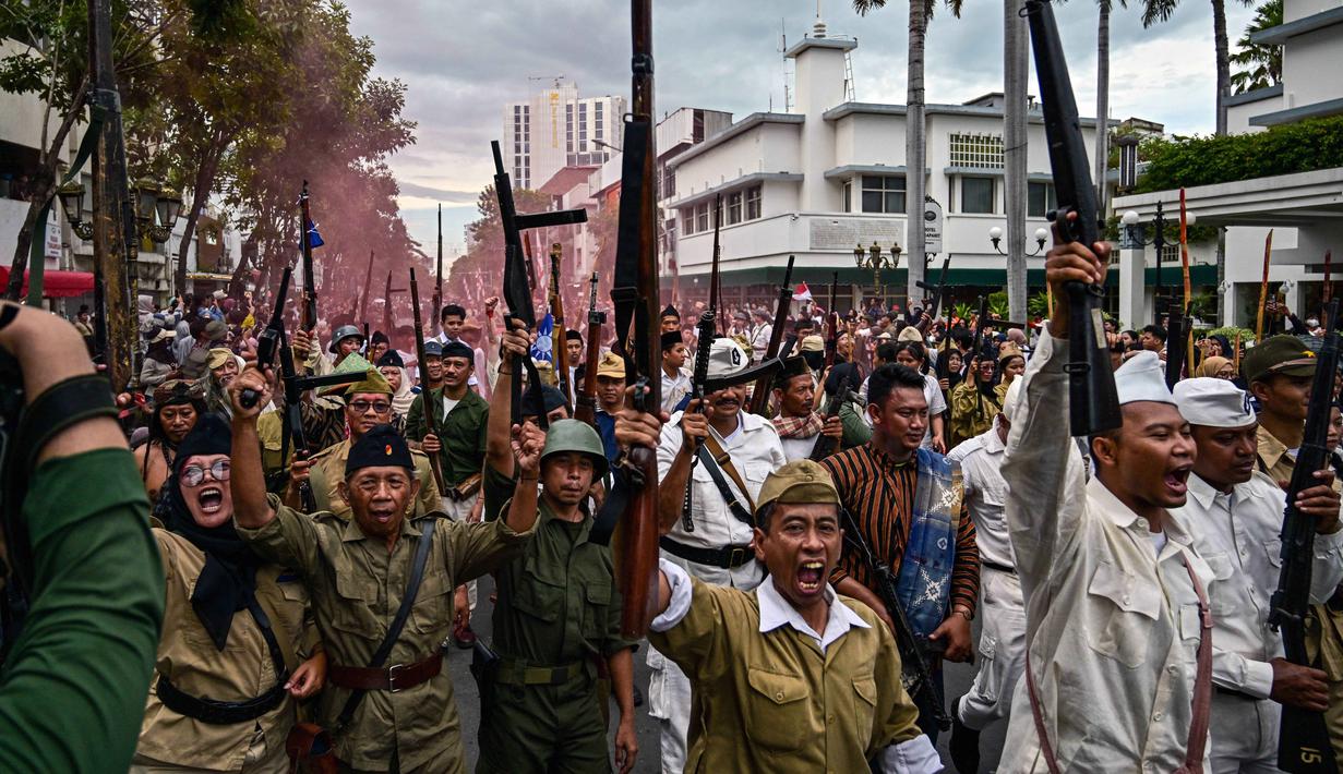 Anggota Komunitas Roode Brug Soerabaia dan Reenactor Indonesia berpartisipasi dalam reka ulang Pertempuran Surabaya, pada Minggu 2 November 2025. Anggota komunitas sejarah Roode Brug Soerabaia dan Reenactor Indonesia menggelar reka ulang peristiwa Pertempuran Surabaya, di sekitar kawasan Tugu Pahlawan hingga Balai Pemuda, Kota Surabaya, Jawa Timur, Minggu 2 November 2025. (Juni KRISWANTO/AFP)