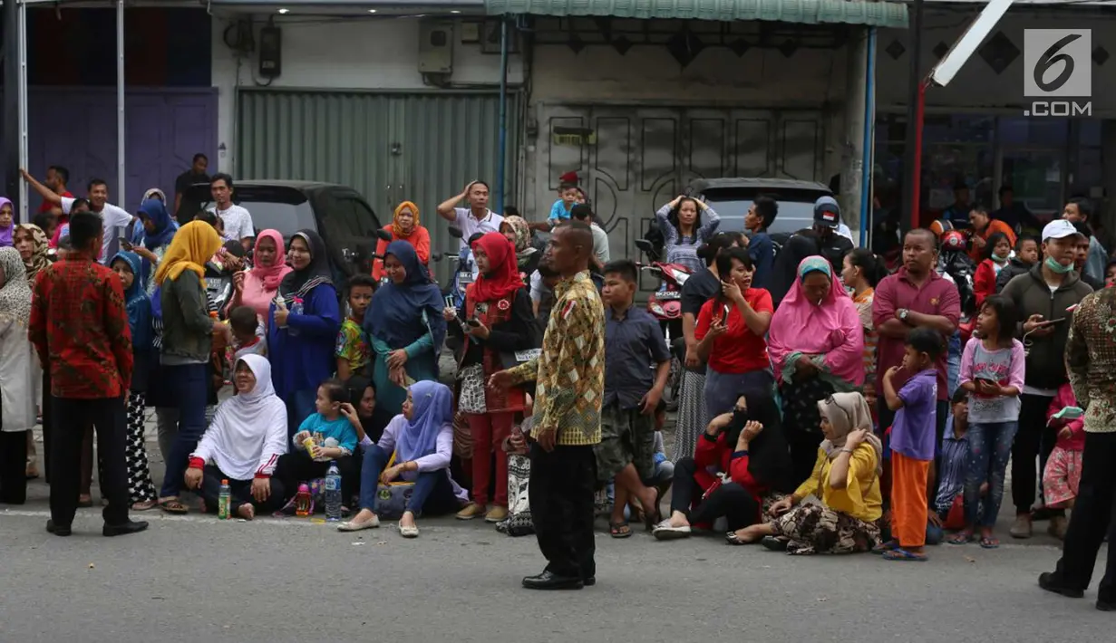 Warga duduk di jalan jelang kirab atau arak-arakan acara resepsi Kahiyang Ayu Siregar-Bobby Nasution di Kota Medan, Sumatera Utara Minggu (26/11). (Liputan6.com/Johan Tallo)