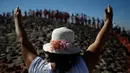 Seorang wanita mengangkat tangannya untuk menerima energi matahari saat merayakan equinox musim semi di situs arkeologi Teotihuacan, Meksiko (21/3). (AP Photo/Rebecca Blackwell)
