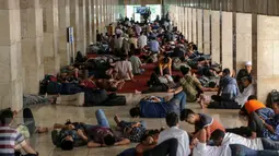 Umat muslim bersantai di koridor Masjid Istiqlal, Jakarta, Jumat (19/6). Selain membaca Alquran, sejak memasuki bulan Ramadan, warga setiap hari memenuhi Masjid Istiqlal untuk beristrahat sambil menunggu waktu berbuka puasa. (Liputan6.com/Faizal Fanani)