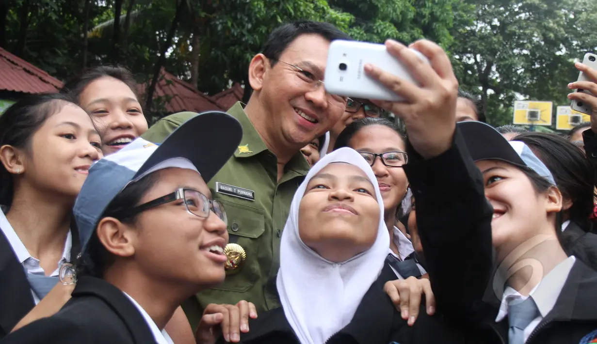 Sejumlah siswa SMKN 27 Jakarta ber-selfie bersama Gubernur DKI Basuki 'Ahok' Tjahaja Purnama sebelum memulai Ujian Nasional (UN), Senin (13/4/2015). (Liputan6.com/Herman Zakharia)