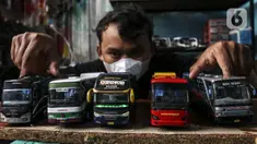 Perajin memamerkan miniatur bus di Workshop Belang Bentong, Limo, Depok, Jawa Barat, Jumat (14/1/2022). Kerajinan miniatur bus berbahan baku akrilik dan resin tersebut dipasarkan ke berbagai daerah dengan harga Rp 700 ribu hingga Rp 1 juta per unit. (Liputan6.com/Johan Tallo)
