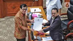 Menteri Hukum dan HAM RI Yasonna Laoly (kiri) menyerahkan RUU kepada Wakil Ketua Komisi III DPR RI Pangeran Khairul Saleh (kanan) saat Rapat Kerja dengan Komisi III DPR RI di gedung Parlemen, Jakarta, Senin (5/12/2022). Rapat kerja membahas RUU tentang pengesahan perjanjian antara Pemerintah Republik Indonesia dengan Pemerintah Republik Singapura tentang ekstradisi buronan. (Liputan6.com/Angga Yuniar)