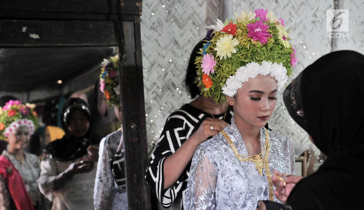 Gadis dirias oleh keluarga sebelum mengikuti Upacara Adat Ngarot di Desa Lelea, Kabupaten Indramayu, Jawa Barat, Rabu (19/12). Ngarot digelar sebagai bentuk rasa syukur menjelang musim tanam padi. (Merdeka.com/Iqbal Nugroho)