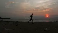 Seorang peserta Sunset Trail Run melintasi pantai pada Festival Pesona Tanjung Lesung 2017 di Tanjung Lesung, Banten (23/9/2017). Sunset Trail Run tersebut menempuh jarak 16 km. (Bola.com/Nicklas Hanoatubun)