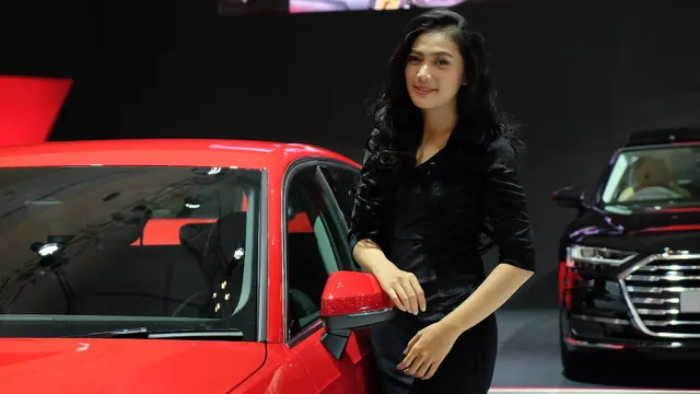 Usher berpose di samping mobil Audi