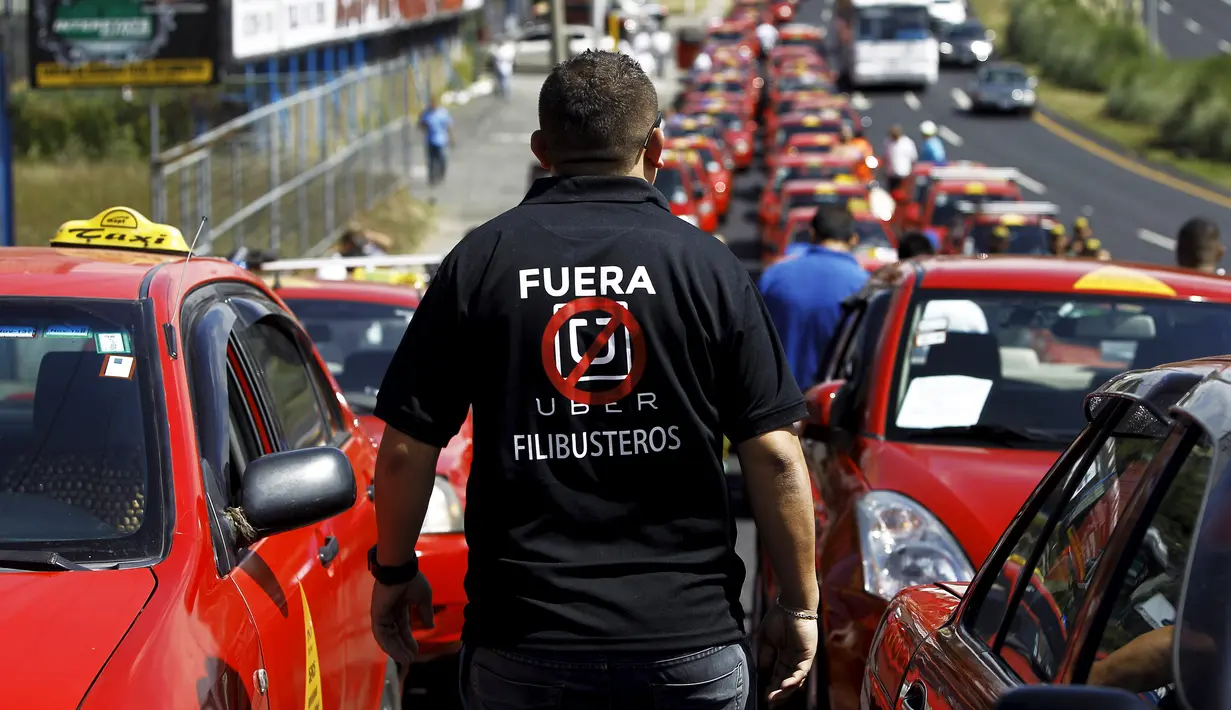 Seorang sopir taksi mengenakan kaos bertuliskan "Uber, keluar dari Kosta Rika" saat menggelar unjuk rasa di San Jose, Senin (1/2).  Mereka melakukan protes terhadap taksi Uber yang mulai beroperasi di Kosta Rika. (REUTERS/Juan Carlos Ulate)