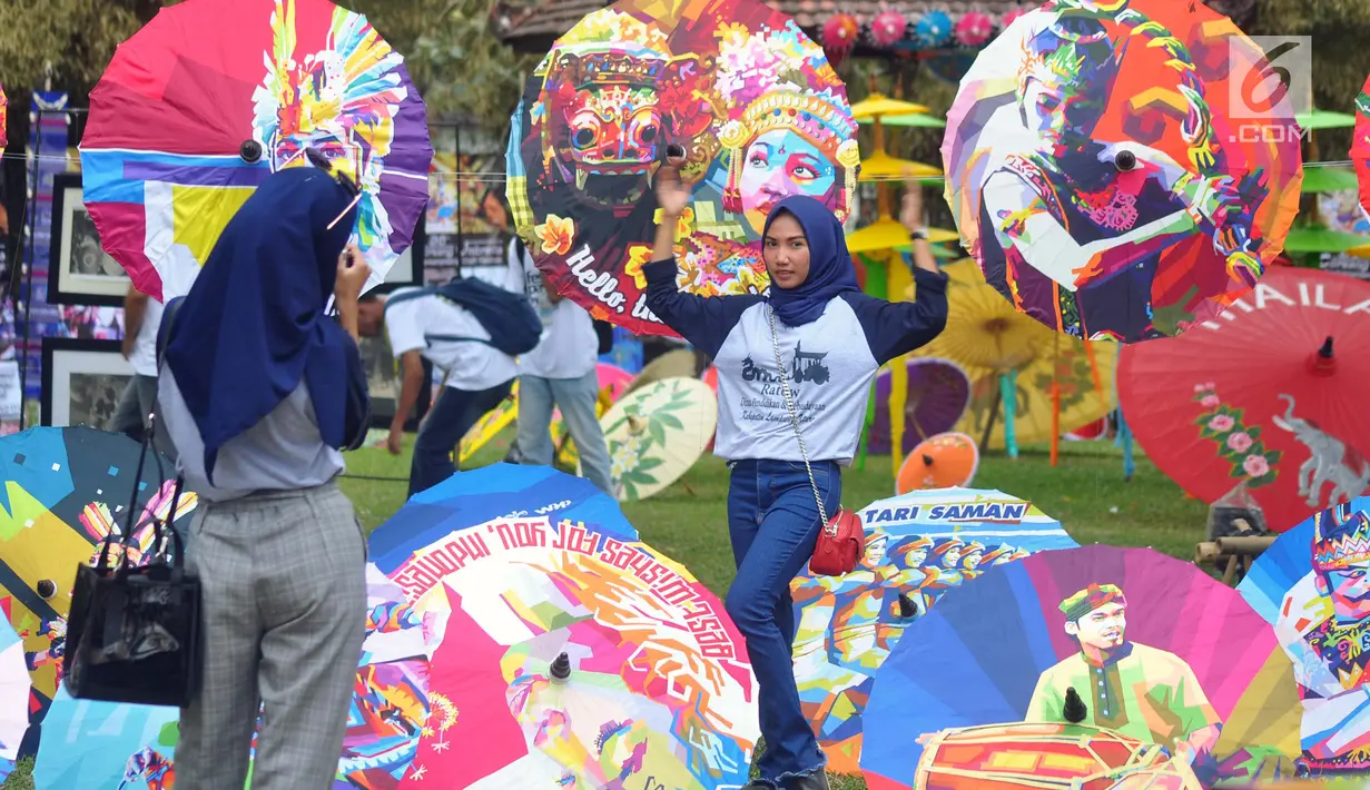 Pengunjung berfoto dekat dekorasi payung pada Festival Payung Indonesia 2018 di Taman Lumbini, Komplek Candi Borobudur, Magelang, Jumat (7/9). Festival ini menampilkan aneka macam tradisi dan kreasi masyarakat dalam bentuk payung. (Liputan6.com/Gholib)