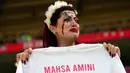 Seorang suporter Iran menangis sambil memegang kaos bertuliskan 'Mahsa Amini' sebelum dimulainya pertandingan sepak bola Grup B Piala Dunia 2022 antara Wales dan Iran di Ahmad Bin Ali Stadium, Al Rayyan, Qatar, Jumat (25/11/2022). (AP Photo/Alessandra Tarantino)