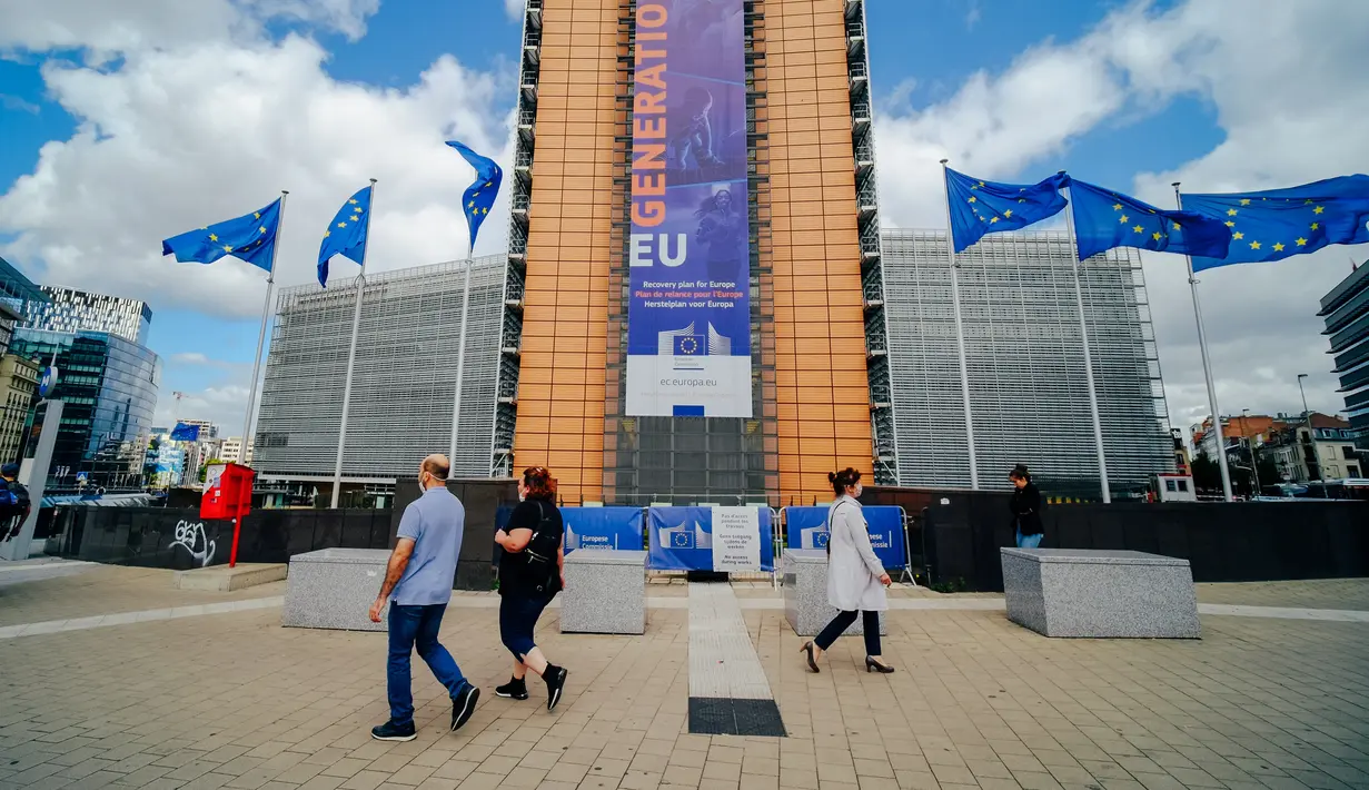 Warga mengenakan masker saat berjalan melintasi kantor pusat Komisi Eropa di Brussel, Belgia, Senin (29/6/2020). Kepala Organisasi Kesehatan Dunia (WHO) mengatakan bahwa semua negara yang hidup dengan COVID-19 akan menjadi suatu kondisi normal baru dalam beberapa bulan mendatang.(Xinhua/Zhang Cheng)