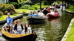 Turis bersama anjingnya menaiki perahu menyusuri sungai di Giethoorn yang menjadi tujuan wisata favorit di Belanda, 6 Agustus 2019. Mendapat julukan 'Venice of the North', kota tersebut menggunakan kanal-kanal sebagai jalan dan lalu lalang transportasi sehari-hari. (Robin van Lonkhuijsen/ANP/AFP)