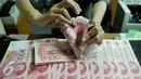Petugas menghitung uang pecahan 100 Yuan, Jakarta, Kamis (13/8/2015). Biang kerok keterpurukan kurs rupiah dan sejumlah mata uang negara lain adalah kebijakan China yang sengaja melemahkan (devaluasi) mata uang Yuan. (Liputan6.com/Johan Tallo)