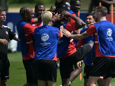 Pelatih Kanada AS Jesse Marsch (kiri) menyaksikan bek Kanada #15 Moise Lumpungu (tengah) diajak bercanda oleh rekan satu timnya selama sesi Latihan sehari sebelum semifinal Copa America 2024 di Basking Ridge, New Jersey, Senin (8/7/2024). (JUAN MABROMATA / AFP)
