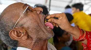 Seorang pasien menelan ikan murrel hidup dengan ramuan obat asma yang diberikan oleh keluarga Bathini Goud, di tempat pameran di Hyderabad, India, Jumat (9/6/2023). (Photo by Noah SEELAM / AFP)