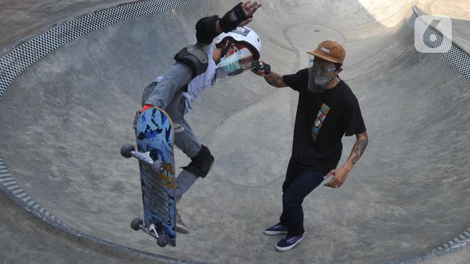 Instruktur melatih seorang anak menggunakan skateboard dengan memakai masker dan face shield di Crooz Shophouse di kawasan Duren Tiga, Jakarta Selatan, Minggu (2/8/2020). Mereka kembali melakukan latihan seminggu dua kali dengan menerapkan protokol kesehatan. (merdeka.com/Arie Basuki)