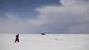 Sepasang suami istri berjalan di Salar de Uyuni, dataran garam terbesar di dunia, di Uyuni, Bolivia, pada 7 November 2020. Dikenal sebagai dataran garam terluas di dunia karena Salar de Uyuni memiliki luas sekitar 4.086 kilometer persegi. (RONALDO SCHEMIDT/AFP)