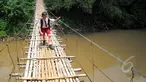 Seorang siswa SD melintas di atas jembatan gantung di atas kali Ciliwung untuk menuju ke sekolah, Jakarta, Selasa (17/3/2015). Jembatan tersebut menghubungkan Kelapa Dua Depok dengan Lenteng Agung (Liputan6.com/Yoppy Renato)