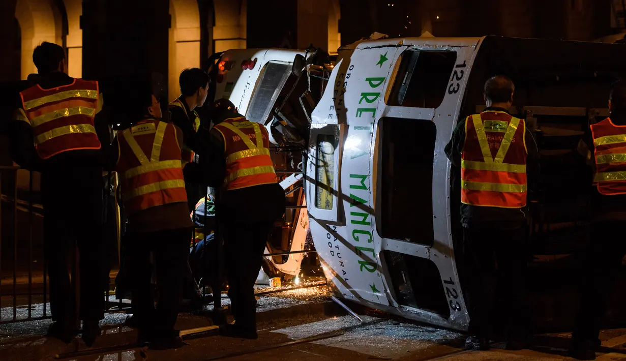 Regu penolong berusaha mengevakuasi trem double-decker yang terbalik di jalan utama di Hong Kong, Kamis (6/4). Kecelakaan yang terjadi tengah malam waktu setempat itu mengakibatkan 11 orang mengalami luka-luka. (ANTHONY WALLACE/AFP)