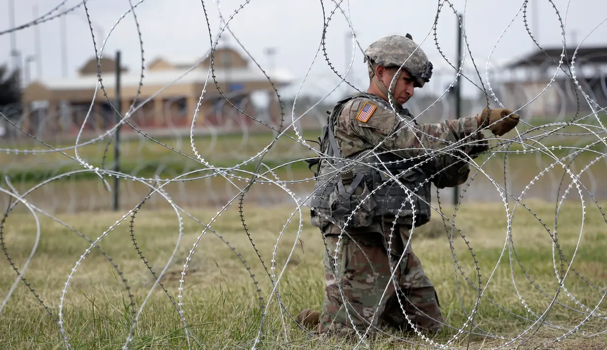 Tentara AS memasang kawat duri dekat Jembatan Internasional AS-Meksiko di Donna, Texas, Minggu (4/11). Label imigran bermotif ekonomi disematkan pada mereka yang ingin mencari kehidupan lebih baik dan melarikan diri dari kemiskinan. (AP Photo/Eric Gay)