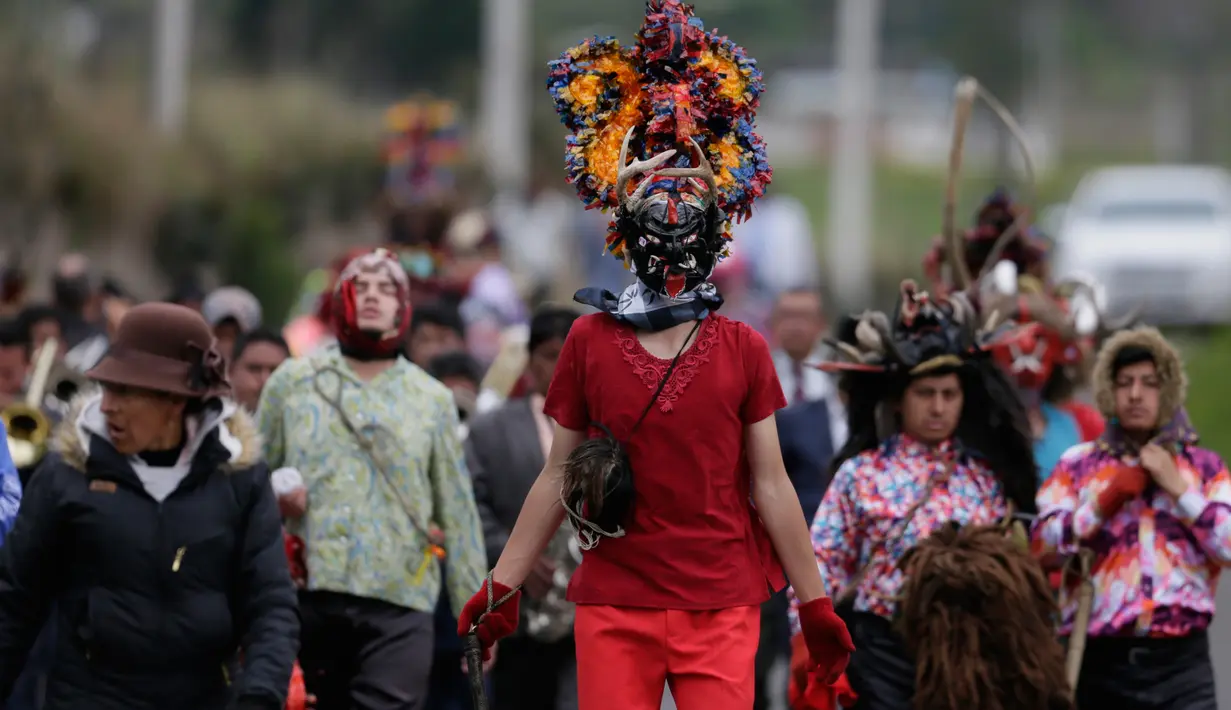 Warga mengenakan topeng setan sambil menari selama festival  La Diablada di jalan-jalan kota Pillaro, Ekuador, Jumat (4/1). Anak-anak, pria, dan wanita memakai aneka pakaian menyeramkan menakut-nakuti orang-orang yang dilaluinya. (AP/Dolores Ochoa)