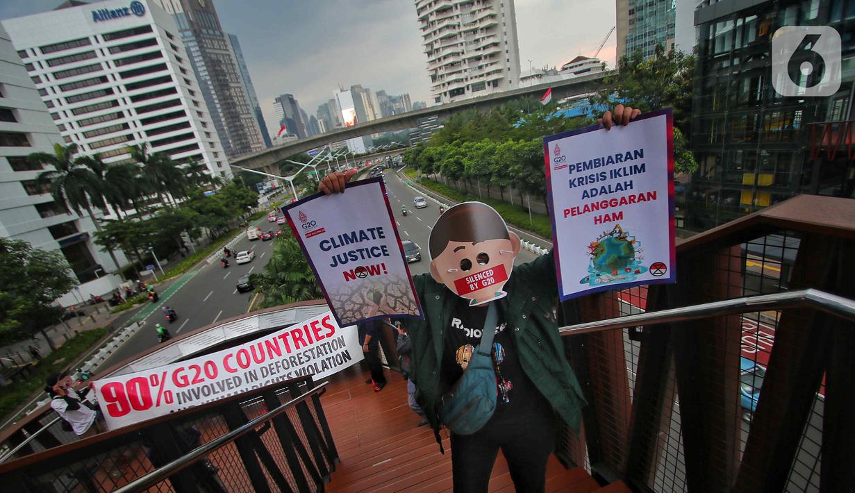 Sejumlah aktivis yang tergabung dalam Extintion Rebellion (XR) dan Walhi Jakarta melakukan aksi di JPO Pinisi, Jalan Jenderal Sudirman, Jakarta, Senin (14/11/2022). Aksi tersebut dilakukan untuk menyerukan kepada para pemimpin agar menghentikan “pencucian hijau” dan praktik ekonomi “business-as-usual” yang secara sistematis memperburuk krisis iklim dan mendorong umat manusia pada kehancuran ekologis & kepunahan massal. Negara-negara G20 turut menyumbang atas 80 persen emisi karbon dunia dan 60 persen populasi penduduk bumi. (Liputan6.com/Angga Yuniar)