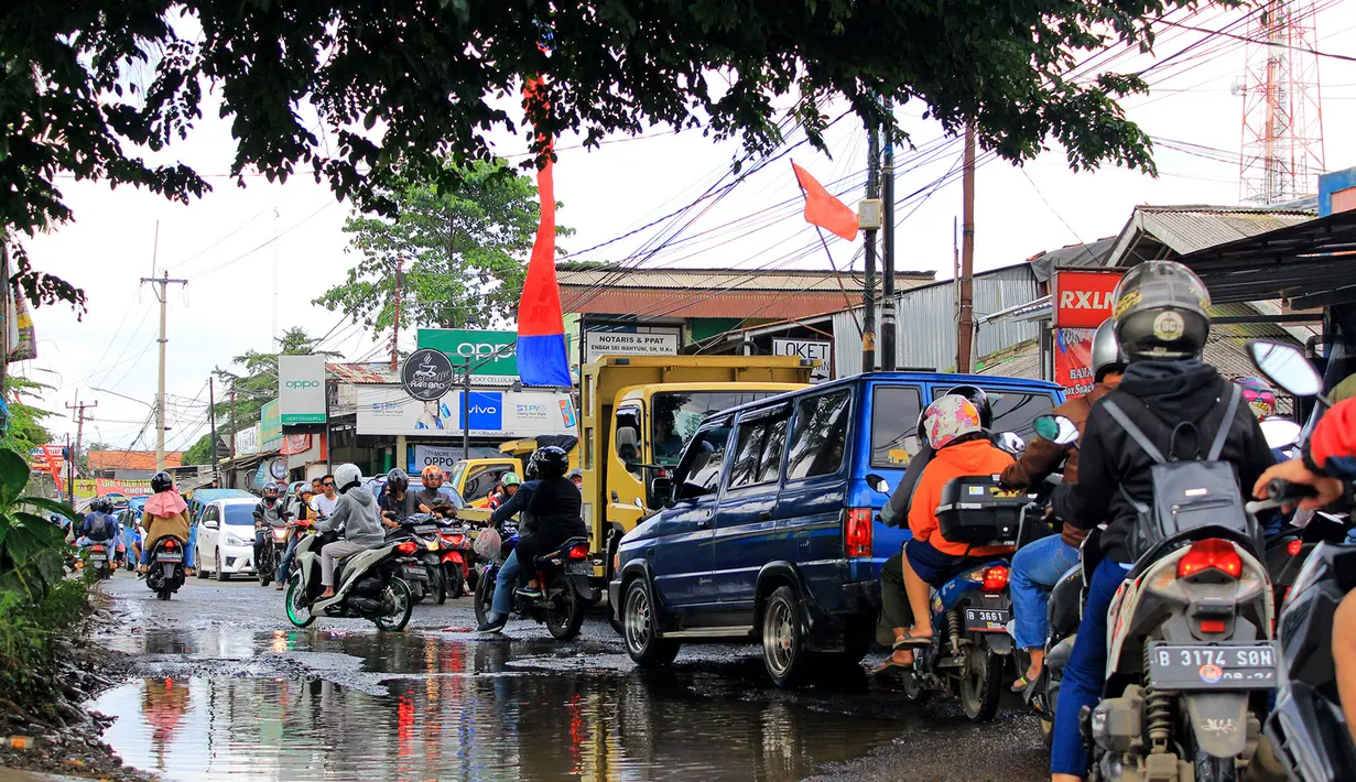 Kendaraan menerobos lubang yang ada di Jalan Raya Bojonggede, Bogor, Jawa Barat, Sabtu (22/2/2020). Jalan Raya Bojonggede yang berlubang hingga kini belum juga diperbaiki pemerintah setempat membuat kondisi lalu lintas tersendat (merdeka.com/Magang/Muhammad Fayyadh)