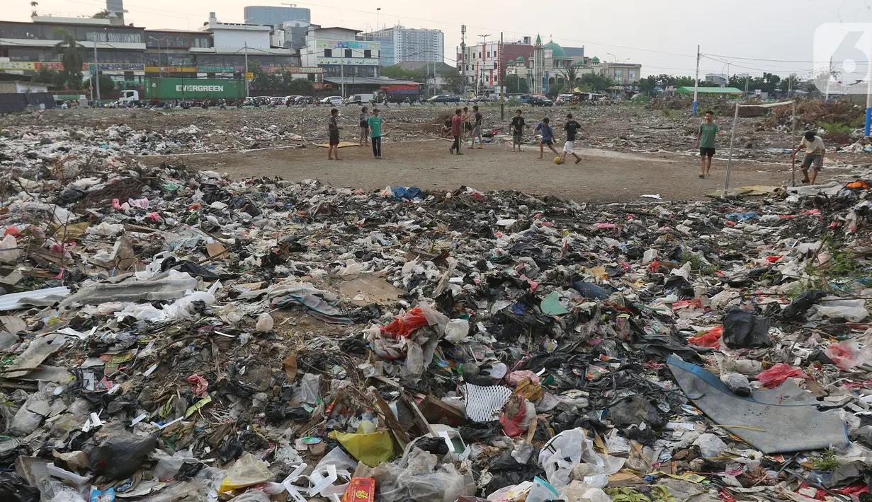 Sejumlah warga bermain sepak bola di antara tumpukan sampah di kawasan Penjaringan, Jakarta, Jumat (1/11/2019). Minimnya lahan bermain di Jakarta membuat warga bermain sepak bola di sekitar tumpukan sampah. (Liputan6.com/Herman Zakharia)