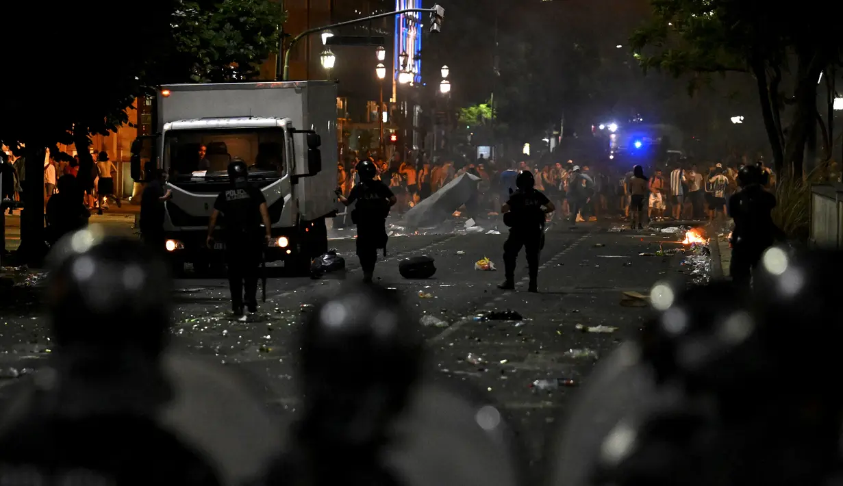 Polisi anti huru hara bentrok dengan suporter setelah perayaan  timnas Argentina meraih juara Piala Dunia Qatar 2022 di lingkungan Obelisk di Buenos Aires (20/12/2022). Jutaan orang kecewa ketika parade bus yang membawa pemain Argentina harus meninggalkan lokasi itu yang menimbulkan gesekan antara supporter dengan petugas keamanan. (AFP/Luis Robayo)