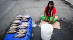 Pedagang menunggu pembeli saat menjajakan ikan dagangannya di sebuah pasar tradisional usai gempa dan tsunami melanda Palu, Sulawesi Tengah, Kamis (4/10). Kebanyakan pedagang berjualan kebutuhan pokok. (Permata SAMAD/AFP)