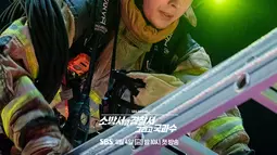 Mengenakan pakaian tahan api, Jin Ho Gae dan Bong Do Jin, yang keduanya diikat dengan tali, terlihat bekerja bersama di ruang di mana api berkobar. Mereka berjuang keras sebagai sebuah tim. (Foto: SBS via Soompi)